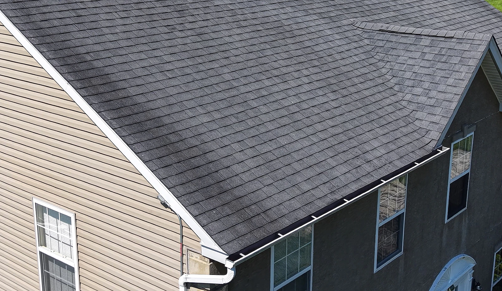 Close-up aerial documentation of a roof valley, gutter line and siding on a residential home