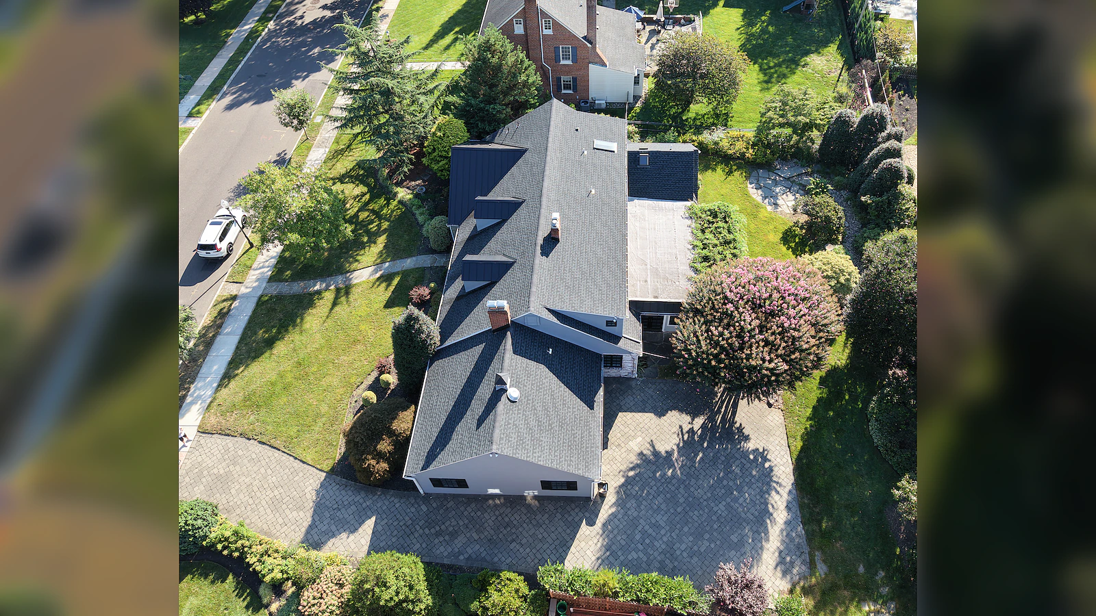 Overhead aerial view of a colonial home, its driveway approach and surrounding grounds