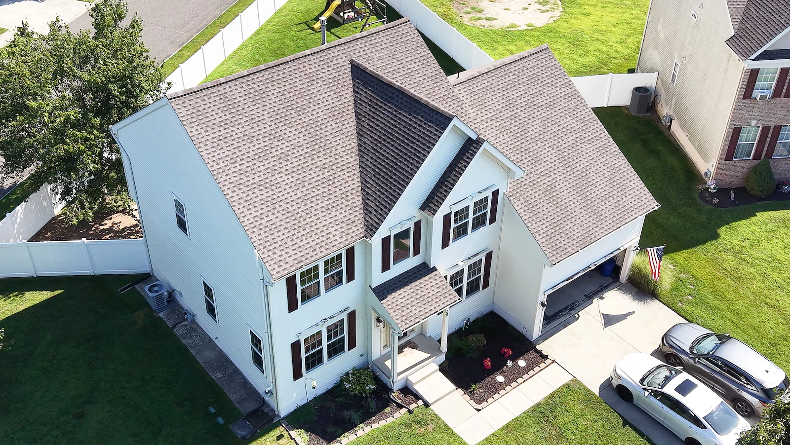 Aerial view of a two-story suburban home showing the front elevation, driveway and fenced rear yard